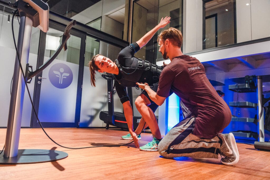 Een dame die aan het sporten is met elektroden, EMS training samen met een personal trainer